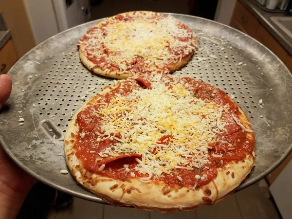 Hand holding metal baking tray with pizzas — Stock Photo, Image