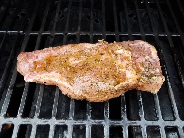 Raw steak meat on barbecue grill rack with liquid — Stock Photo, Image