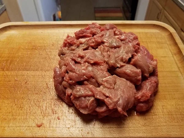 Surowej wołowiny na desce do krojenia drewna w kuchni — Zdjęcie stockowe