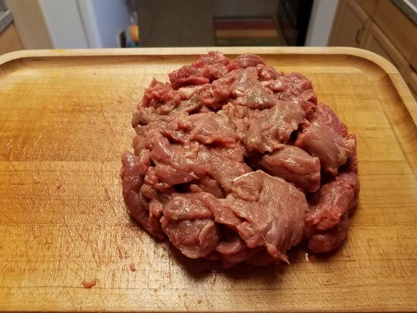 Raw beef on wood cutting board in kitchen — Stock Photo, Image