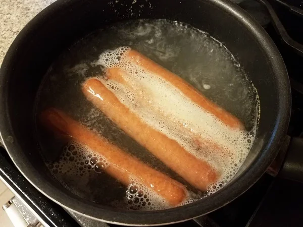 Hot dog bollenti in acqua in padella sui fornelli — Foto Stock
