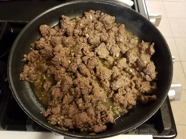 Carne moída e alho em uma panela de ato de fritar no fogão — Fotografia de Stock