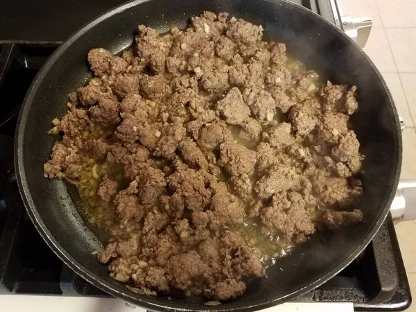 在炉子上的煎锅里把牛肉和大蒜磨碎 — 图库照片