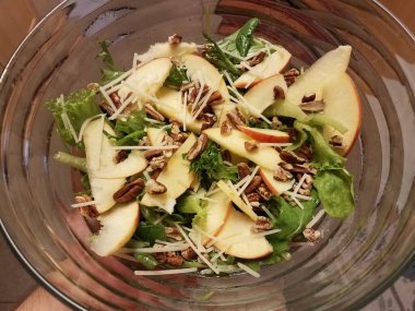 Elinde salata, marul, elma ve fındık dolu cam kaseyle.