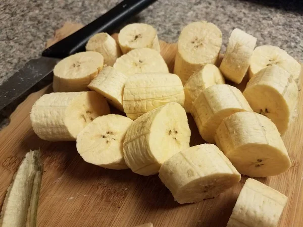 Banana de banana e faca na placa de corte de madeira — Fotografia de Stock