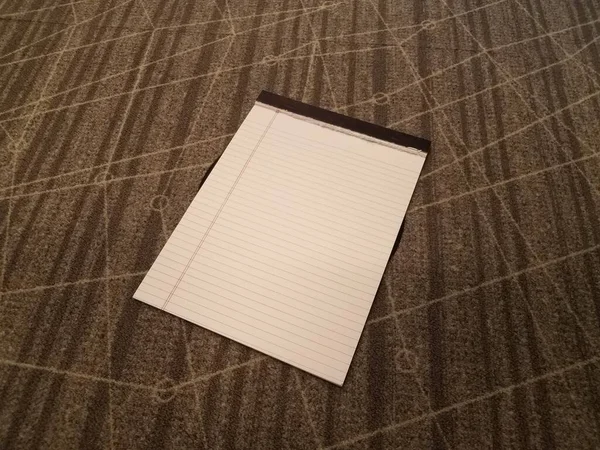Белый блокнот бумаги на сером ковре — стоковое фото