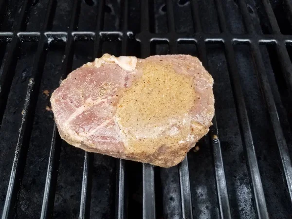 Steak de bœuf cru sur des barres grillées barbecue avec sauce — Photo