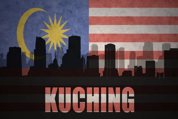 Silueta abstracta de la ciudad con texto Kuching en el fondo de la bandera malaya vintage — Foto de Stock