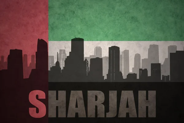 Silhouette astratta della città con testo Sharjah al vintage arabo unito emirates bandiera sfondo — Foto Stock