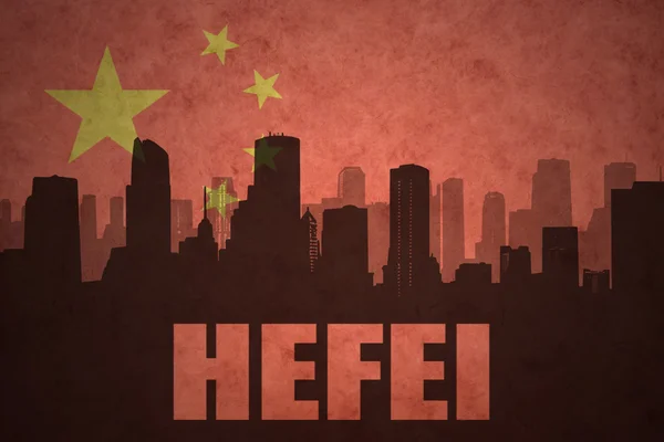 Abstraktní silueta města s textem Hefei na starobylé čínské vlajkové pozadí — Stock fotografie