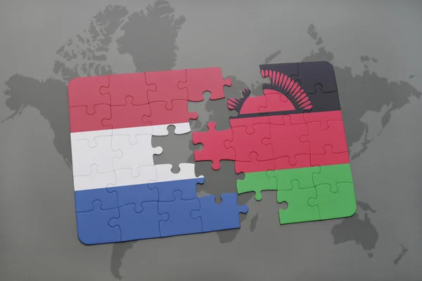 Puzzel met de nationale vlag van Nederland en Malawi op een wereld kaart achtergrond. — Stockfoto