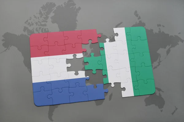 Rompecabezas con la bandera nacional de los Países Bajos y Nigeria en un mapa del mundo fondo . — Foto de Stock