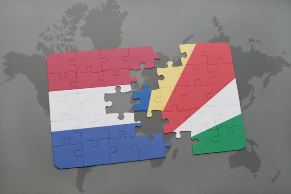 Puzzel met de nationale vlag van Nederland en de Seychellen op een wereld kaart achtergrond. — Stockfoto