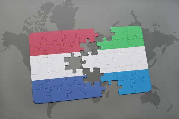 Puzzel met de nationale vlag van Nederland en Sierra Leone op een wereld kaart achtergrond. — Stockfoto