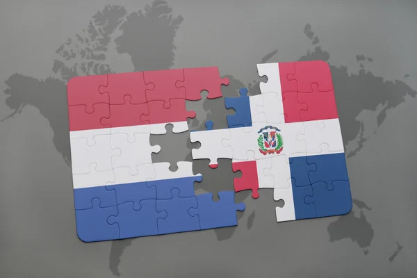 Quebra-cabeça com a bandeira nacional das terras baixas e da república dominicana em um fundo de mapa do mundo . — Fotografia de Stock