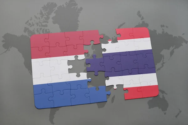 Puzzle avec le drapeau national des Pays-Bas et de Thaïlande sur un fond de carte du monde . — Photo