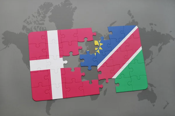 Quebra-cabeça com a bandeira nacional de denmark e namibia em um fundo de mapa do mundo . — Fotografia de Stock