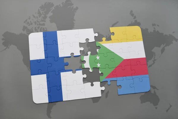 Puzzel met de nationale vlag van Finland en Comoren op een wereld kaart achtergrond. — Stockfoto