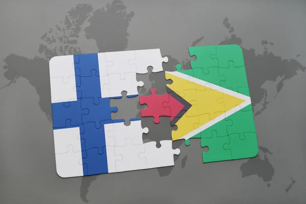 Puzzel met de nationale vlag van Finland en Guyana op een wereld kaart achtergrond. — Stockfoto
