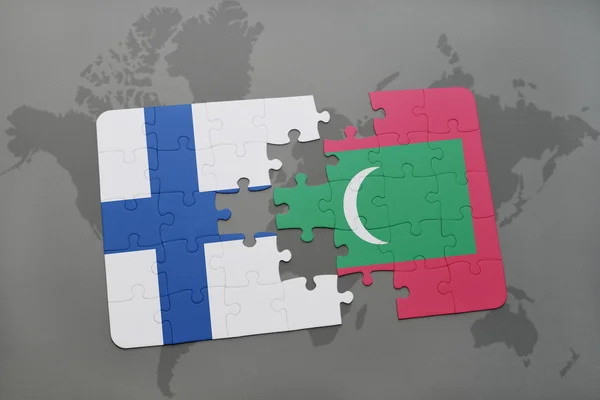 Puzzle con la bandiera nazionale della Finlandia e le maldive su uno sfondo mappa del mondo . — Foto Stock