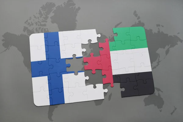 Quebra-cabeça com a bandeira nacional da Finlândia e emirados árabes unidos em um mapa do mundo de fundo . — Fotografia de Stock