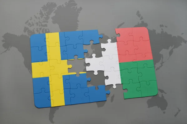 Puzzel met de nationale vlag van Zweden en Madagaskar op een wereld kaart achtergrond. — Stockfoto