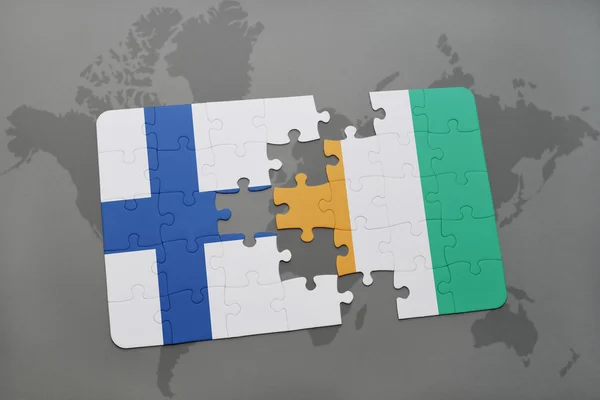 Rompecabezas con la bandera nacional de Finlandia y Costa de Marfil en un mapa del mundo de fondo . —  Fotos de Stock