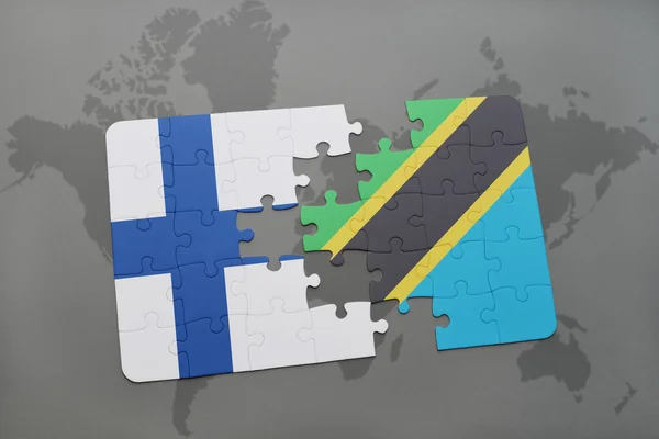 Puzzel met de nationale vlag van finland en tanzania op de achtergrond van een wereld kaart. — Stockfoto