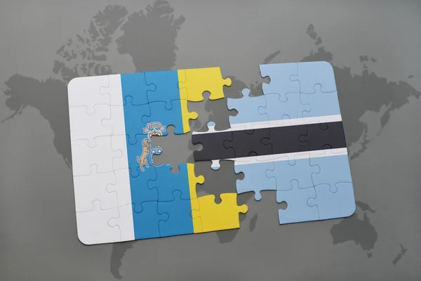 Puzzle with the national flag of canary islands and botswana on a world map background. — Stock Photo, Image