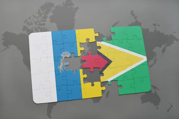 Puzzle with the national flag of canary islands and guyana on a world map background. — Φωτογραφία Αρχείου