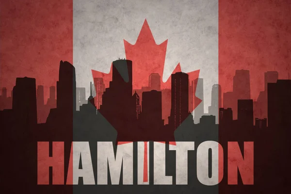 Abstract silhouette of the city with text Hamilton at the vintage canadian flag — Stock Photo, Image