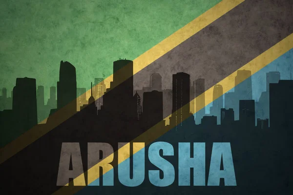 Silhouette astratta della città con testo Arusha alla bandiera tanzana vintage — Foto Stock
