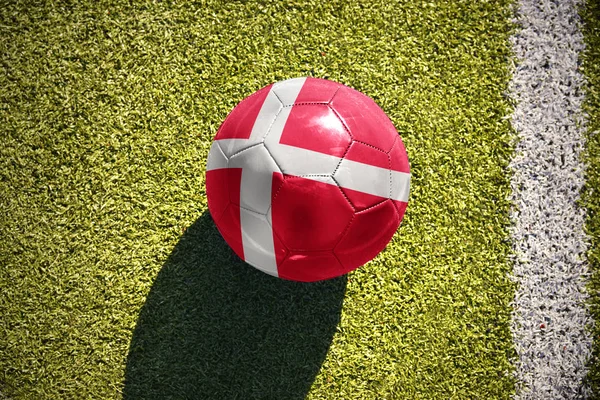 Fotbalový míč s národní vlajkou Dánska leží na hřišti — Stock fotografie