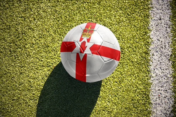 Fotbalový míč s státní vlajka Severního Irska leží na hřišti — Stock fotografie