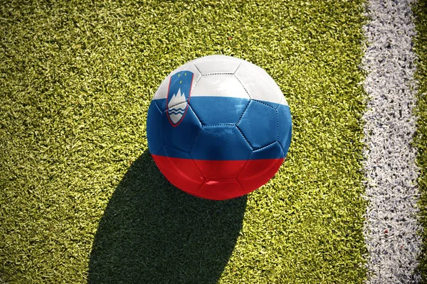 На поле лежит футбольный мяч с национальным флагом Словении — стоковое фото