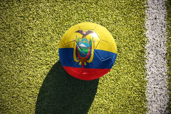 Pelota de fútbol con la bandera nacional del ecuador yace en el campo — Foto de Stock