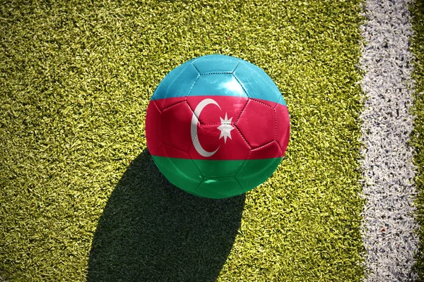 Bola de futebol com a bandeira nacional de azerbaijan encontra-se no campo — Fotografia de Stock