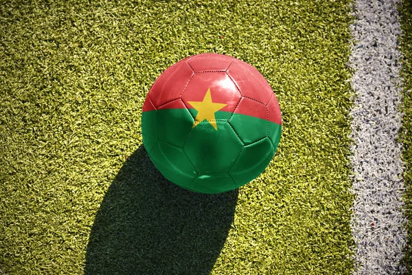 Bola de futebol com a bandeira nacional de burkina faso encontra-se no campo — Fotografia de Stock