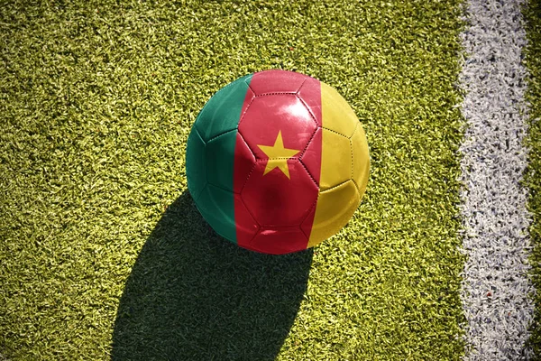 Piłki nożnej z Flaga narodowa Kamerun leży na polu — Zdjęcie stockowe
