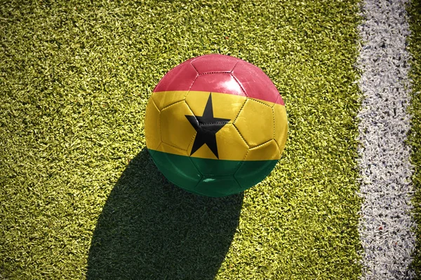 Футбольный мяч с национальным флагом Ганы лежит на поле — стоковое фото