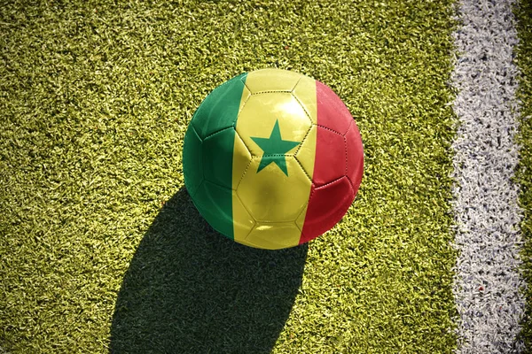 На поле лежит футбольный мяч с национальным флагом Сенегала — стоковое фото