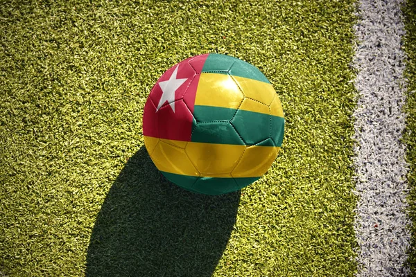 Piłki nożnej z Flaga narodowa togo leży na polu — Zdjęcie stockowe