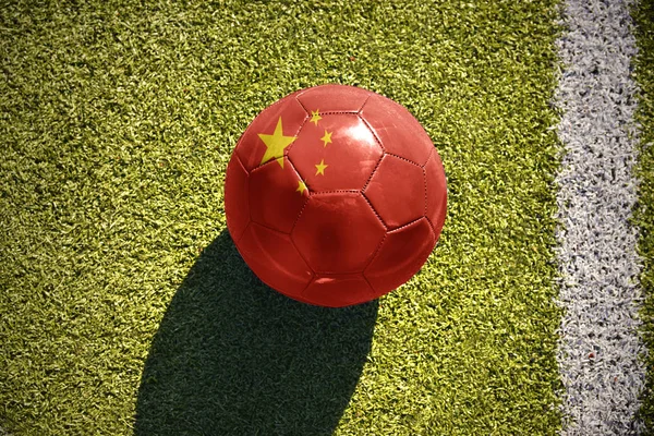 На поле лежит футбольный мяч с китайским флагом — стоковое фото