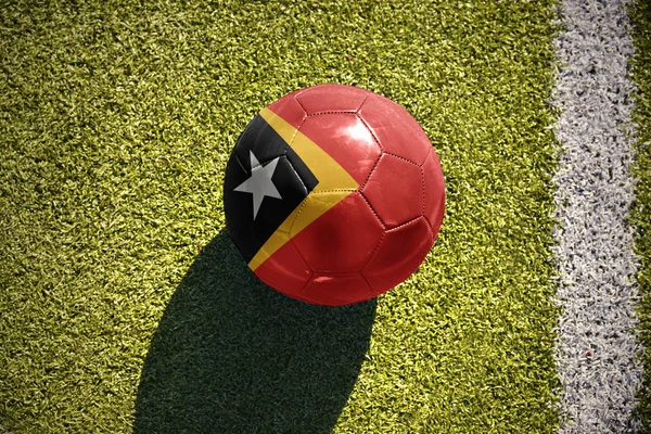 Bola de futebol com a bandeira nacional de timor leste encontra-se no campo — Fotografia de Stock