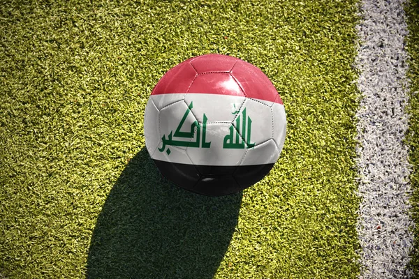 Piłki nożnej z Flaga narodowa Irak leży na polu — Zdjęcie stockowe