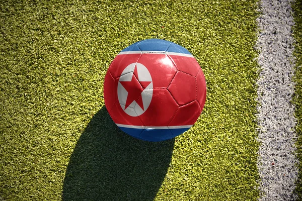 北朝鮮の国旗とサッカー ボールがフィールドにあります。 — ストック写真