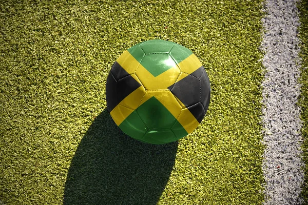 Pelota de fútbol con la bandera nacional de jamaica se encuentra en el campo —  Fotos de Stock