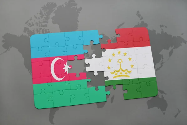 Quebra-cabeça com a bandeira nacional de azerbaijan e tajiquistão em um mapa do mundo — Fotografia de Stock