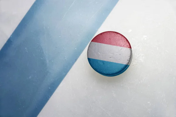 Gamla hockey puck med Luxemburgs flagga. — Stockfoto