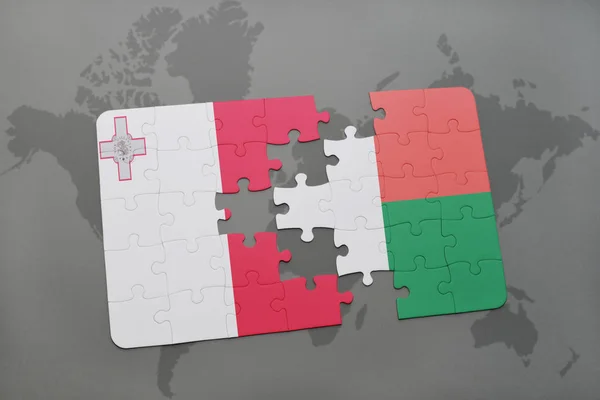 Malta ve Madagaskar ulusal bayrak bir dünya haritası üzerinde ile bulmaca — Stok fotoğraf